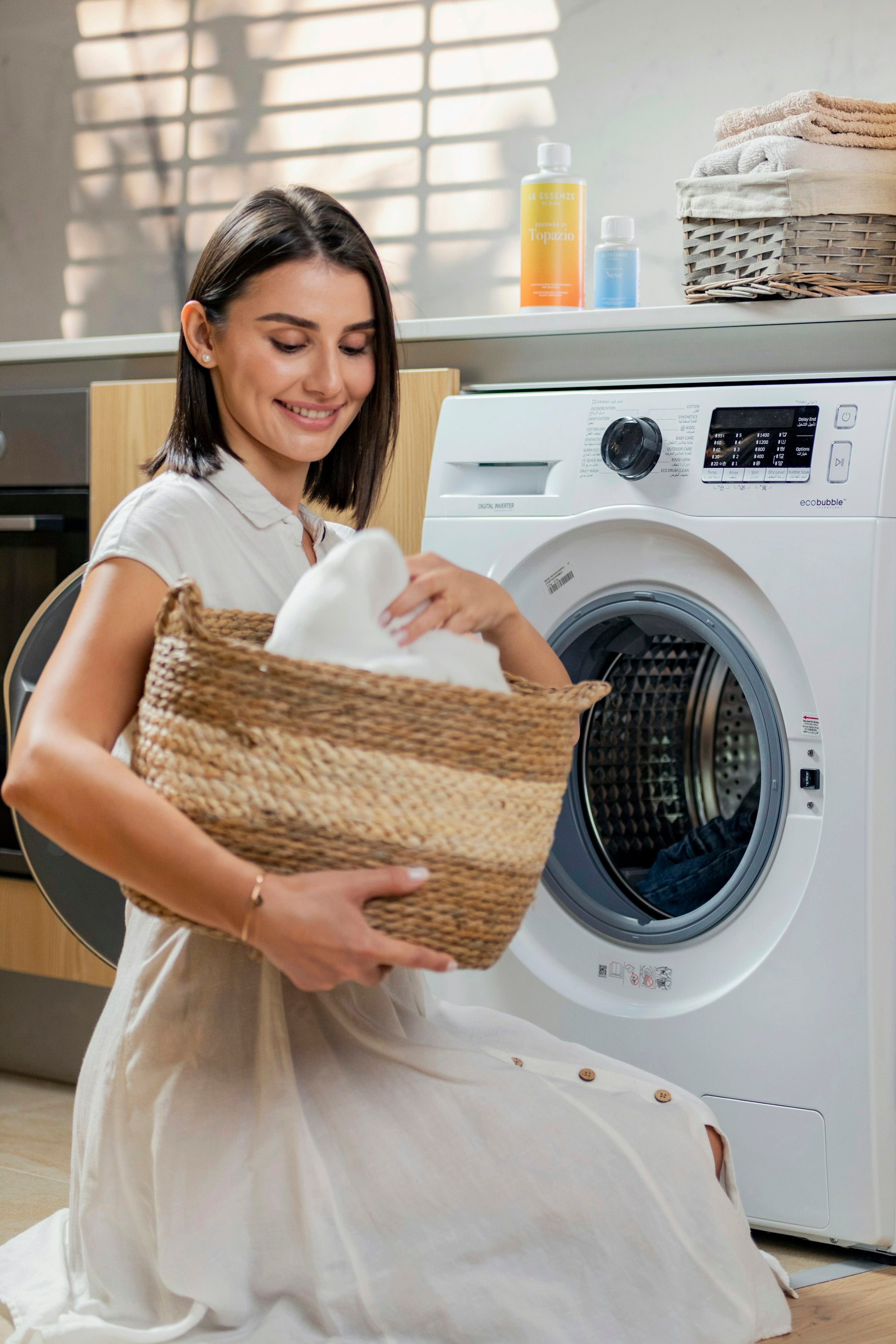 Femme tenant un panier de linge près d'une machine à laver